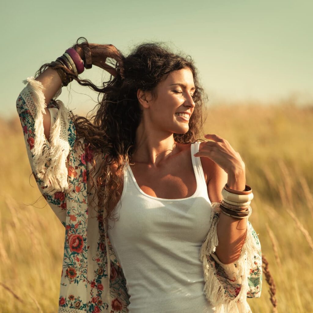 woman stands in a field with a big smile on her face